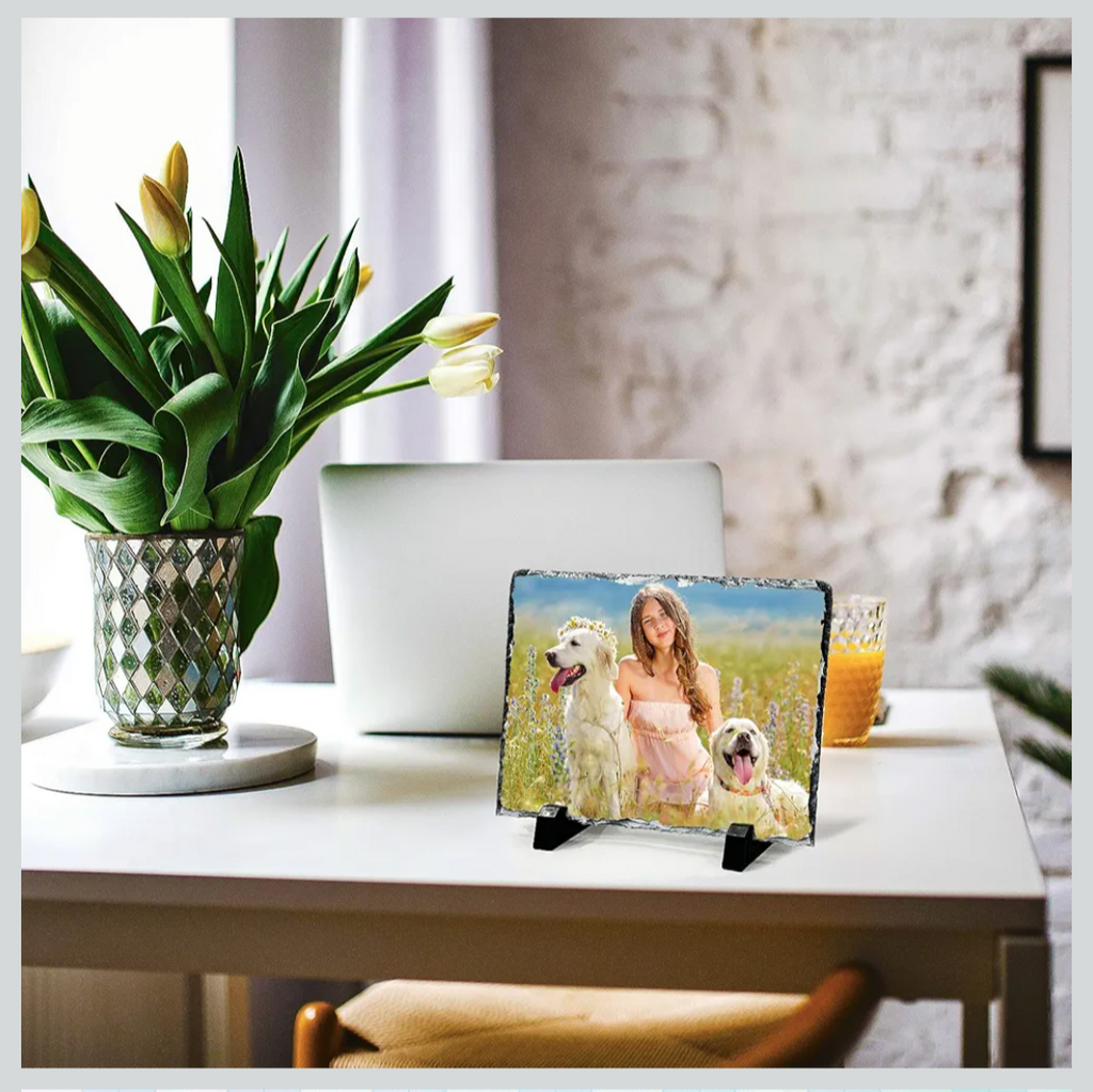 Small table with a decorative item featuring a woman and dogs, a vase of flowers, and a glass of juice.
